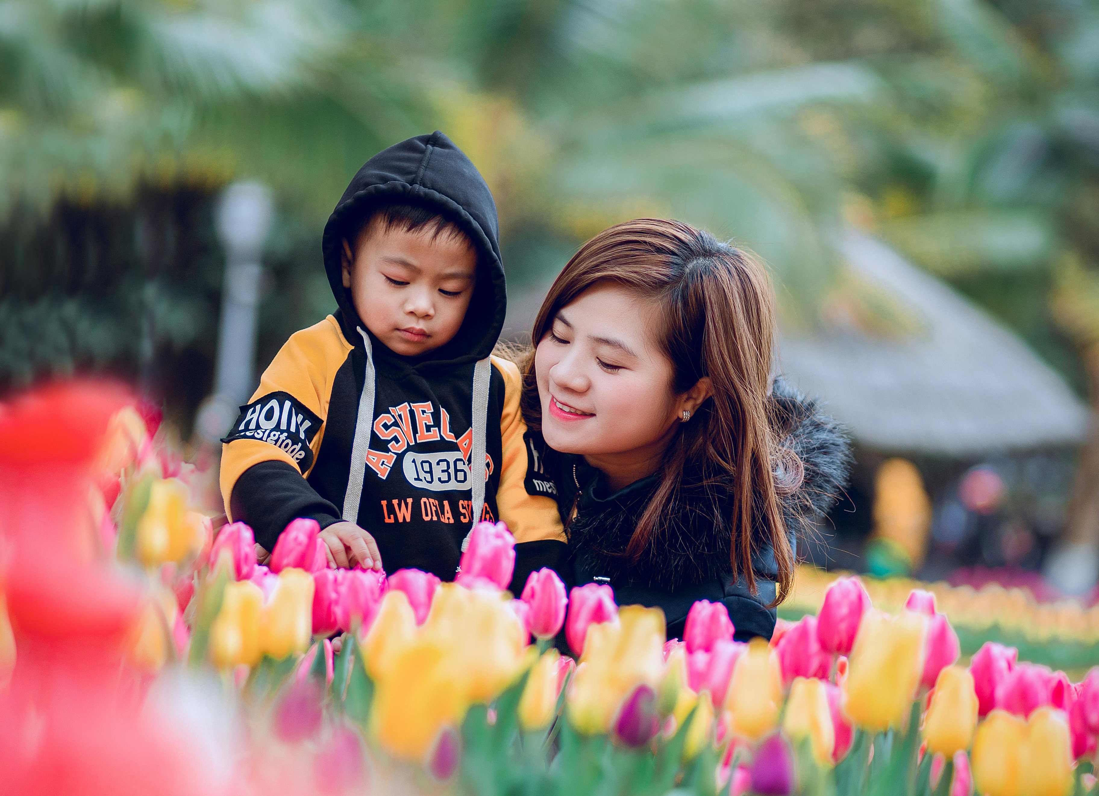 A woman and child are looking at a bed of tulips together